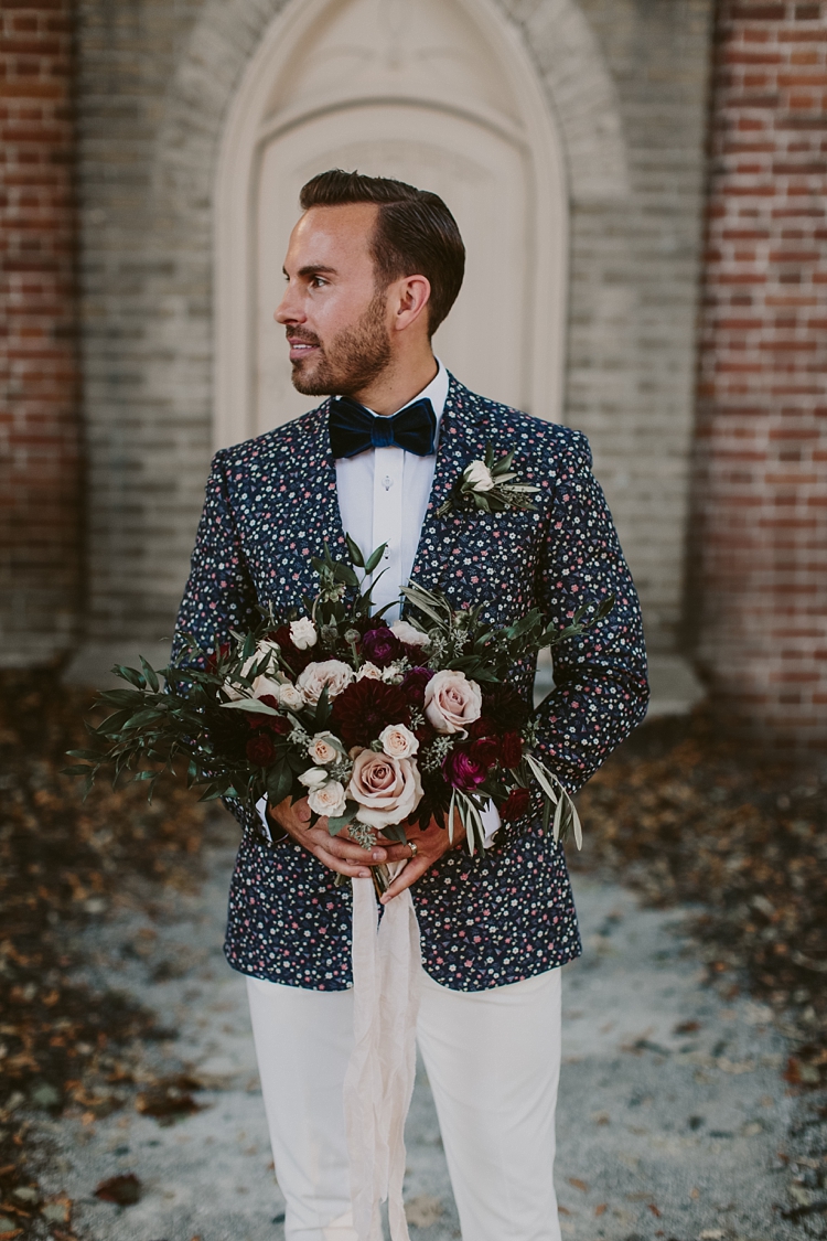 Groom in floral jacket holding flower bouquet